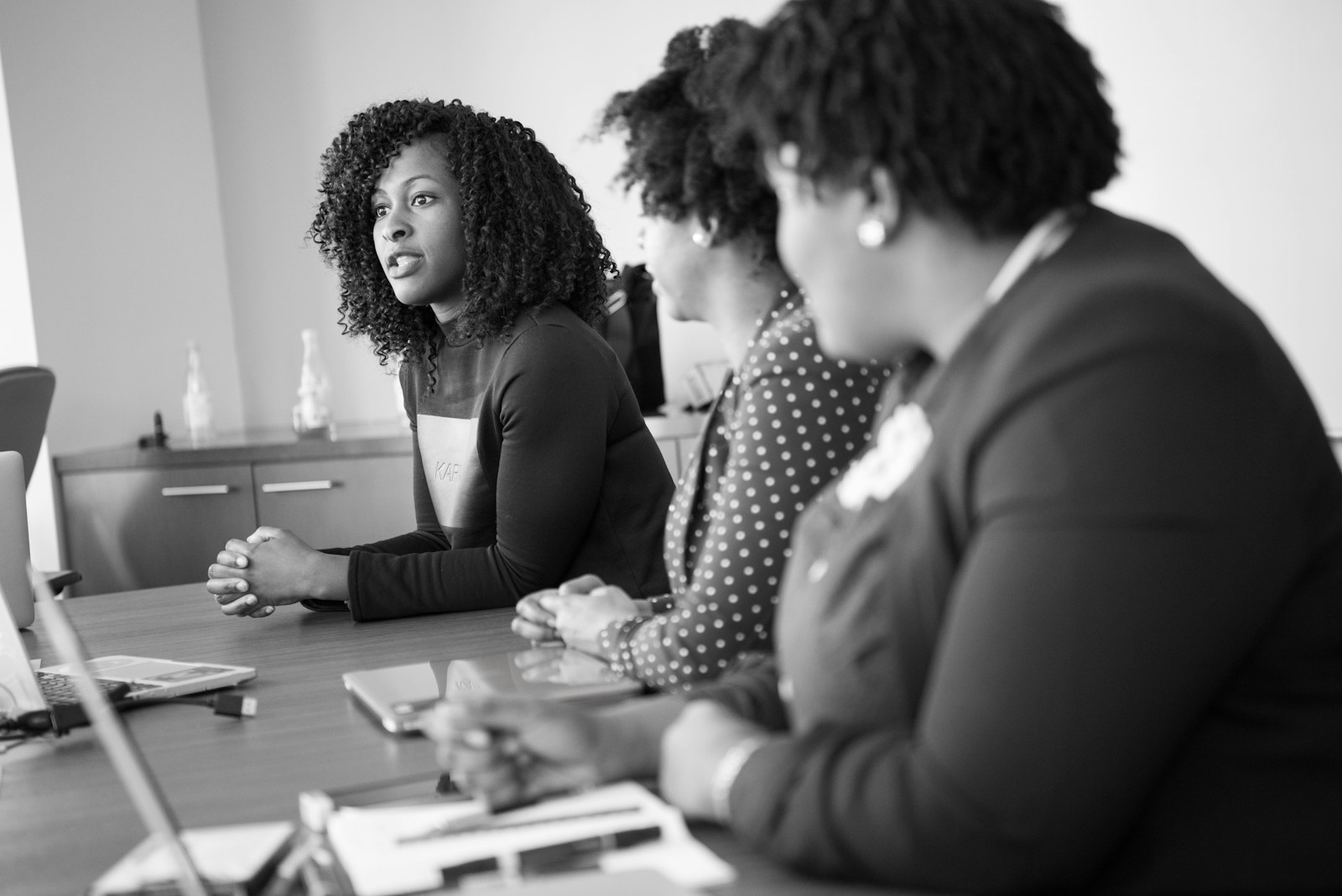 Three professionals in discussion around a meeting table, working through an implementation review.