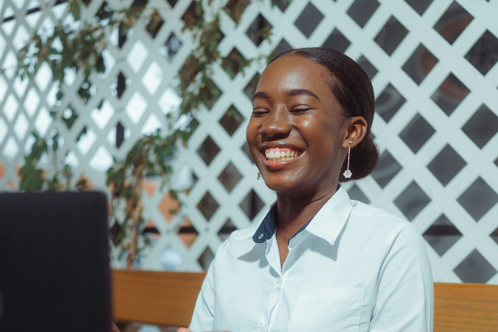 A Ugandan student smiling during an online session at a laptop.