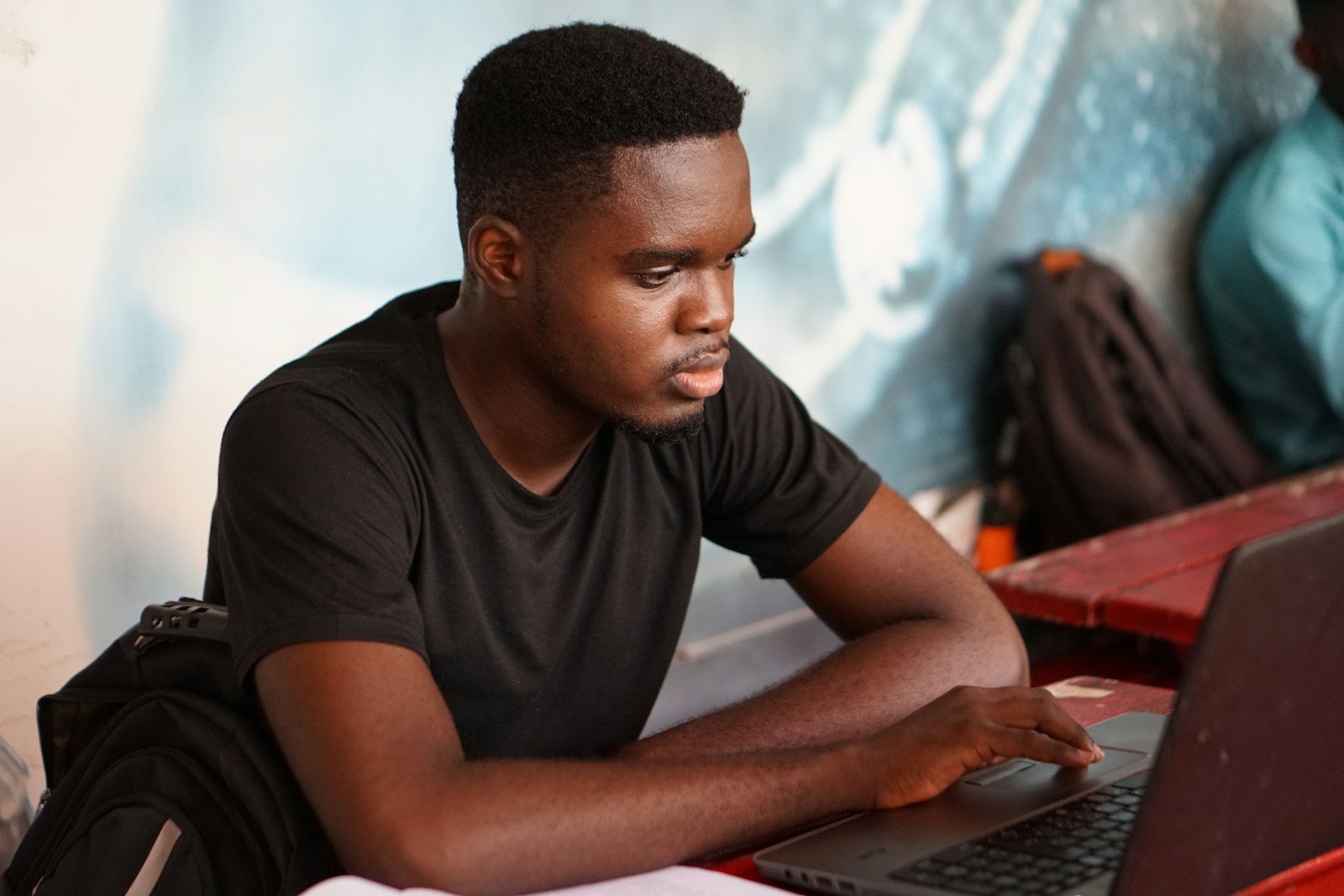 A student concentrating on coursework at a laptop during a training session.
